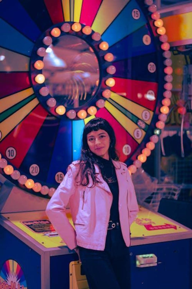 A lady standing against a wheel of luck machine